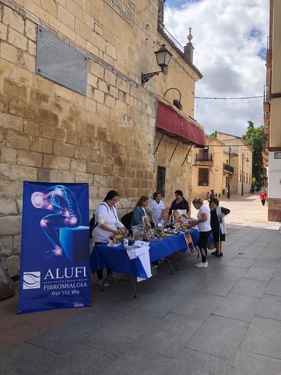 Pancarta de ALUFI junto a la mesa informativa en Plaza Nueva