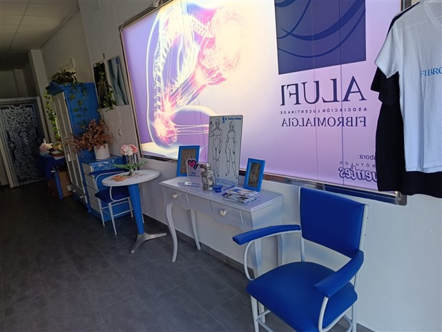 Zona de acogida de ALUFI con sillones azules, plantas y materiales informativos